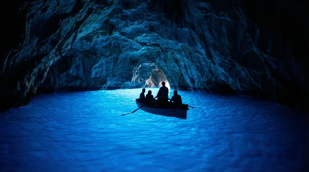 The glowing electric blue waters inside the famous Blue Grotto cave with a small rowboat