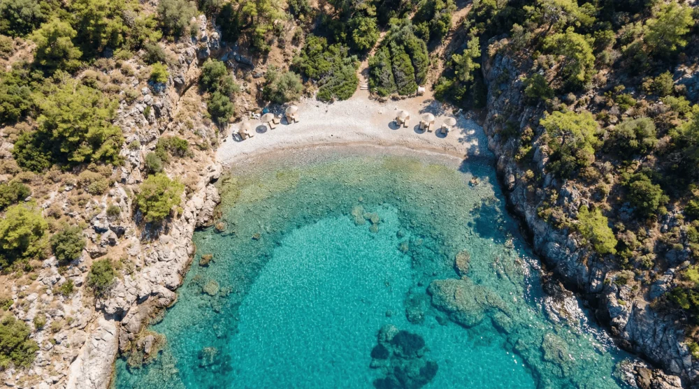 Alman Koyu'nun kristal berraklığındaki turkuaz denizi ve taşlık sahili