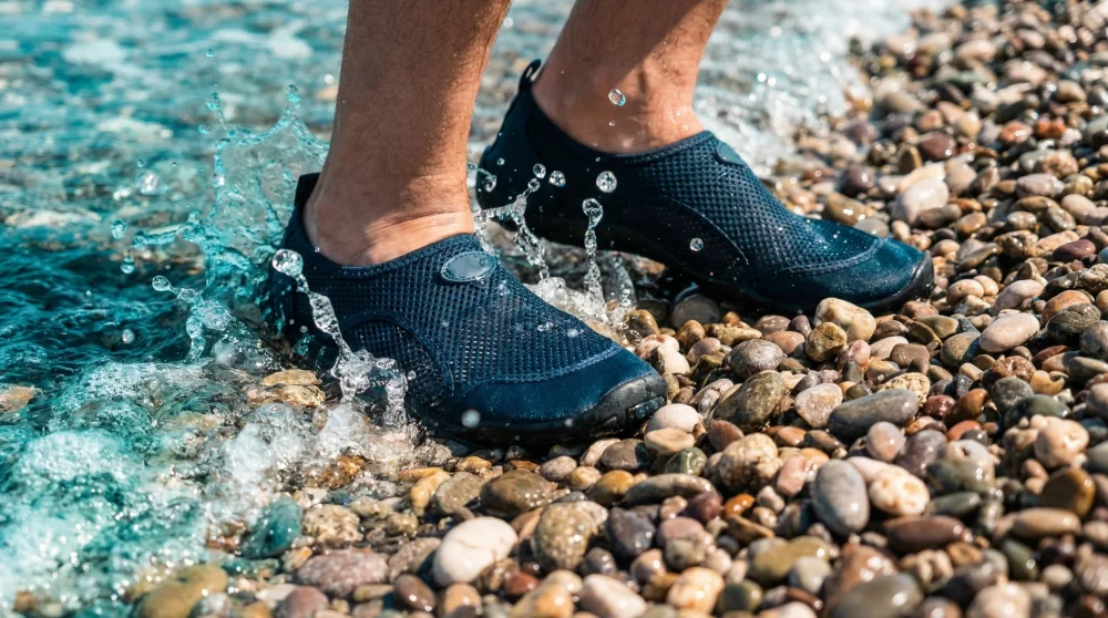 Dat&ccedil;a plajlarındaki taşlı sahilde deniz ayakkabısı ile y&uuml;r&uuml;yen kişi