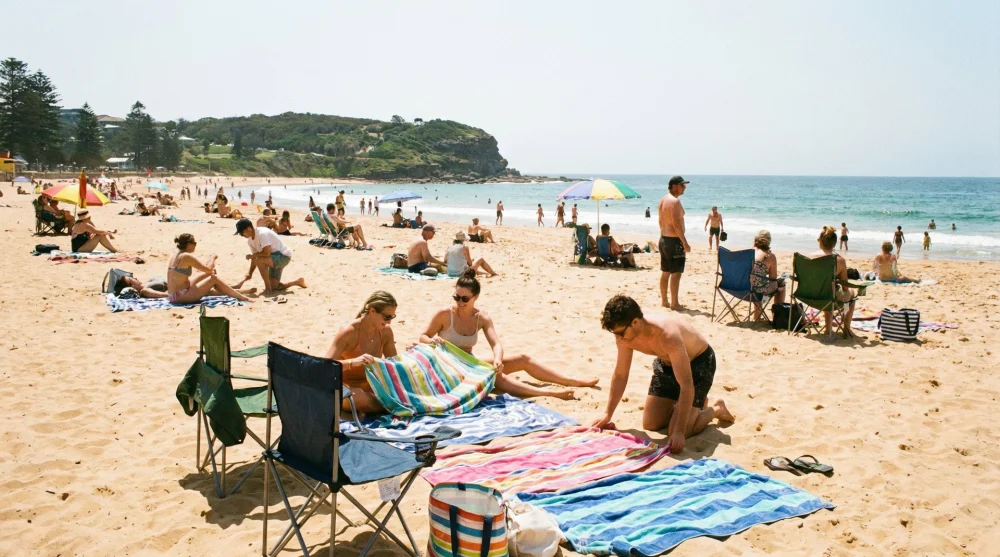 &Uuml;cretsiz halk plajı alanında kendi sandalyesi ve havlusuyla g&uuml;neşlenen tatilciler