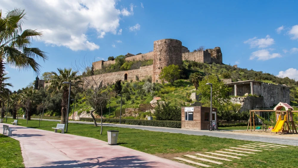 Eskihisar Kalesi'nin tepeden görünümü, aşağıdaki park ve palmiye ağaçlarıyla