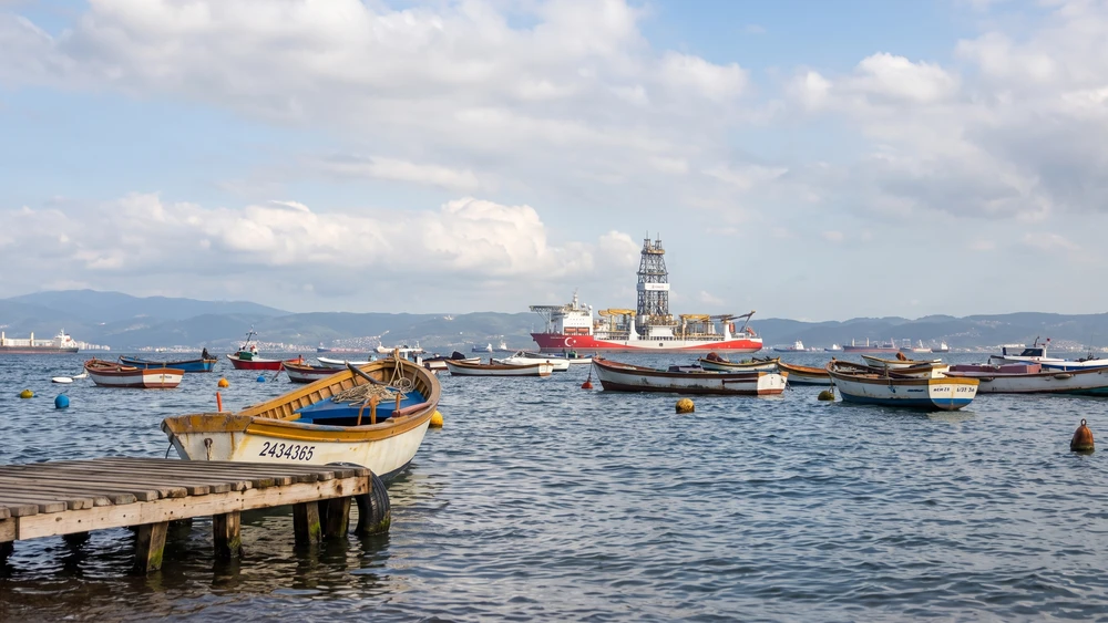 Eskihisar limanında demirli balıkçı tekneleri ve arka planda büyük bir gemi