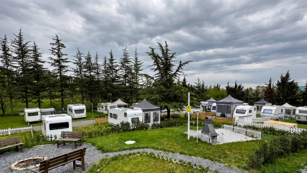 İmaj Camping Karavan Parkı'nda düzenli park edilmiş karavanlar ve çam ağaçları