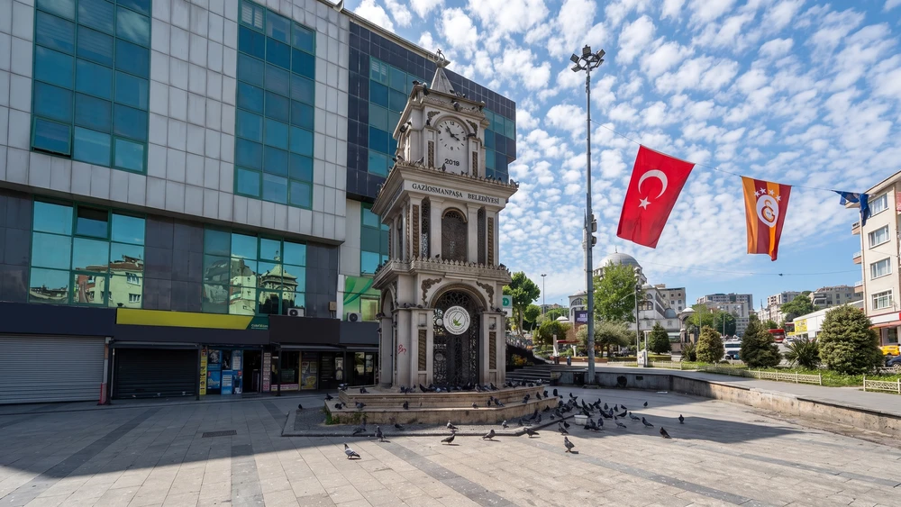 Küçükköy Meydanı'nda tarihî saat kulesi, bayraklar ve taş döşeli açık alan