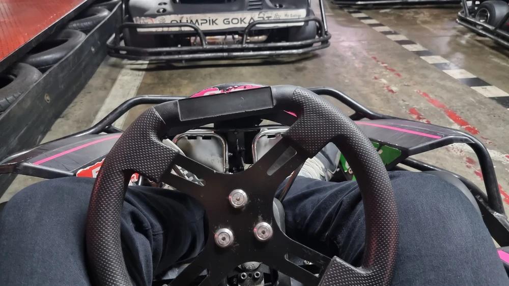 Sürücü gözünden go kart direksiyonu ve pistte önde giden başka bir kart