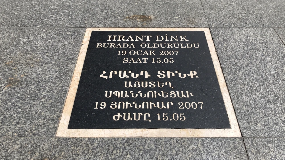 Kaldırımdaki siyah anma plakası, Hrant Dink'in öldürüldüğü yeri Türkçe ve Ermenice yazıyla belirtiyor