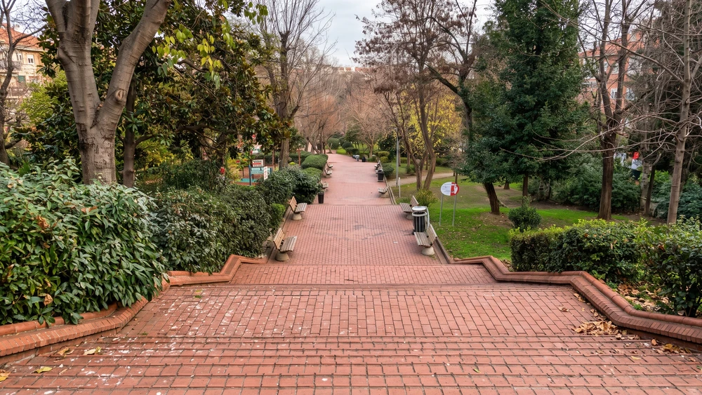 Maçka Demokrasi Parkı'nda kırmızı tuğla merdiven, banklar ve çıplak ağaçlarla çevrili yürüyüş yolu