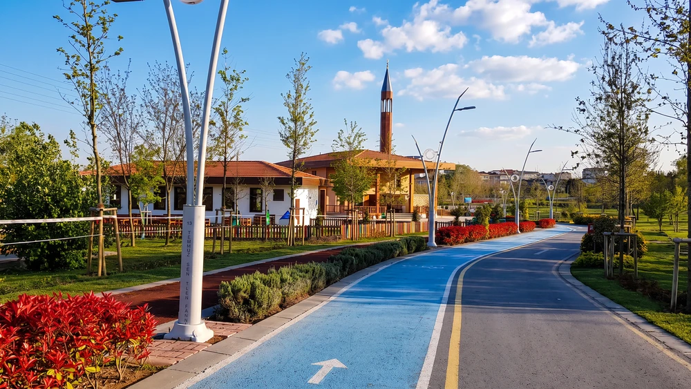 Mavi bisiklet şeridi ve yürüyüş yolu, ucunda küçük bir caminin kırmızı kahverengi minaresi