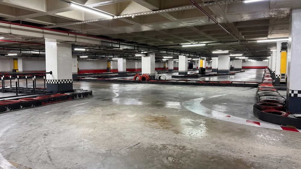 Kareli bantlı kolonlar ve lastik bariyerlerle çevrili kapalı go kart pisti zemini